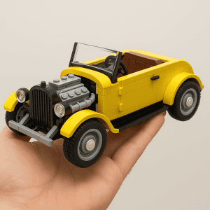 LEGO yellow vintage car toy, detailed with engine and wheels, held in hand on plain background.