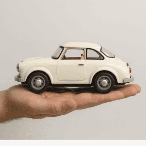 Miniature white car held in hand on a plain background.