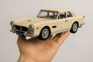 Detailed LEGO model of a vintage beige sports car held in a person's hand.
